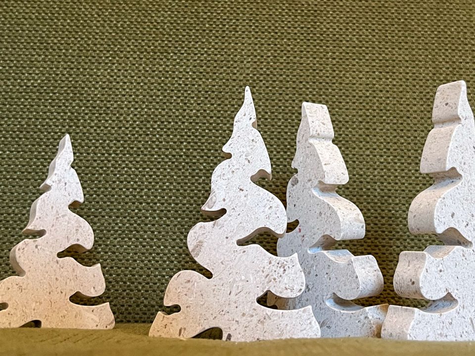 Skup kamenih borova različitih oblika izrađenih od bračkog kamena, suvremeni božićni ukrasi u prirodnim tonovima.